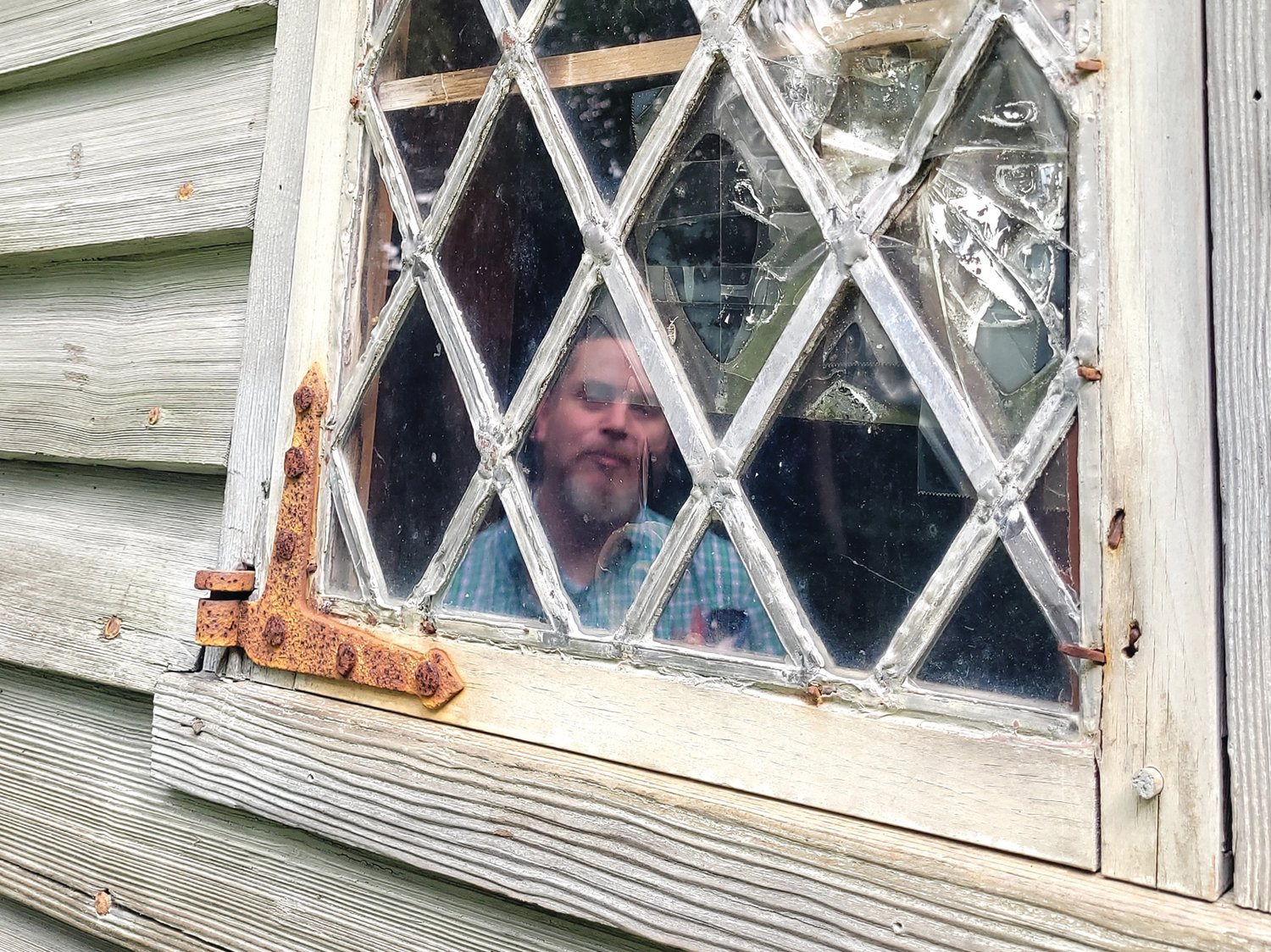 BROKEN GLASS: Historic New England representative Dan Santos, regional site administrator for Southern New England inspects a broken window at the Clemence-Irons House in Johnston.